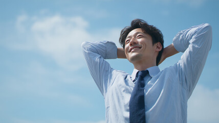 男性がスーツシャツ姿で青空に伸びをする
