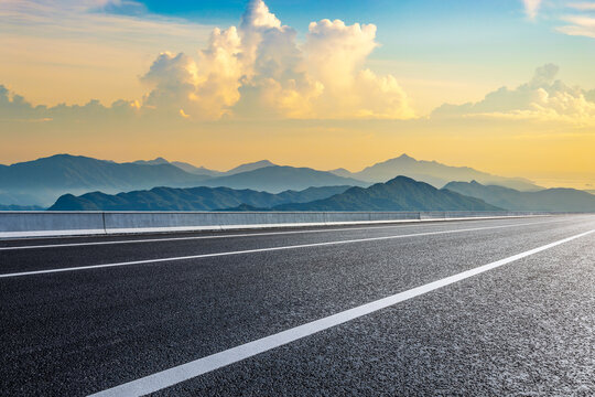 Empty asphalt road and mountain natural landscape under dramatic sky clouds at sunset