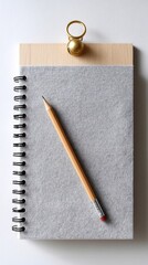 A blank notebook page with a pencil resting on it, pinned to a light gray felt board. 