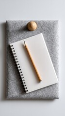 A blank notebook page with a pencil resting on it, pinned to a light gray felt board. 