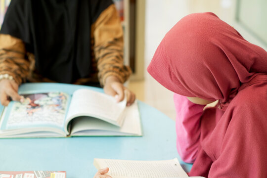 Hiijab girls reading a book at the library