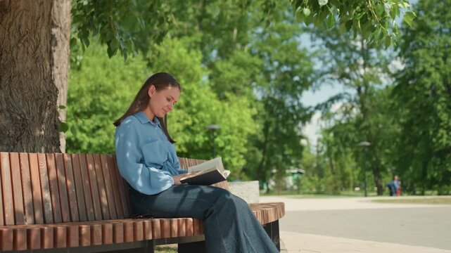 poetry reading outdoors, woman shares poetic verses outside, gentle woman recites poetry beneath trees, lyrical scene of woman softly reciting poetry beneath leafy branches and sunlight