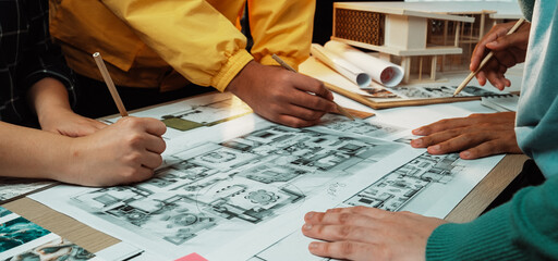 A lively scene showcasing several hands actively collaborating on intricate architectural floor...