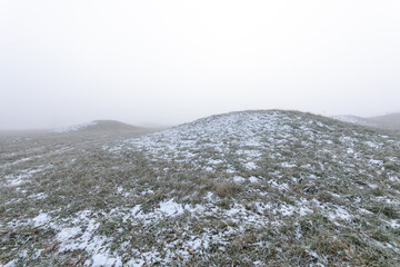 Mystische keltische Grabhügel im Winternebel bei Erkenbrechtsweiler. Verschneite historische Grabstätten am Heidengraben auf der Schwäbischen Alb in atmosphärischer Winterstimmung. © jiriviehmann