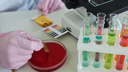 Lab worker conducts experiment with colored liquids and testing samples concept