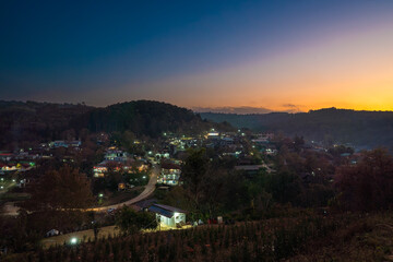 Aerial view of village with Pink Wild Himalayan Cherry tree blooming on twilight , Phitsanulok Thailand from viewpoint hill top