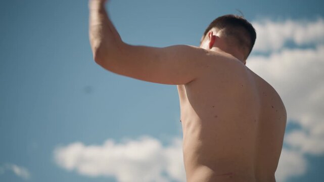 fighter practicing under sunny sky, athlete engaging in dynamic martial arts sequence outdoors, lithe male athlete executing rapid punch movements beneath clear sunny sky with silhouette