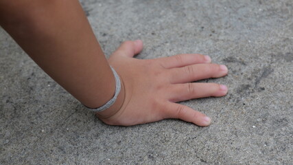 Close-Up of a Child's Hand on a Concrete Surface with a Focus on Textural Details