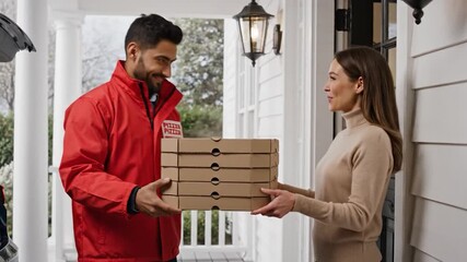 A delivery driver in a red jacket hands pizza boxes to a smiling woman