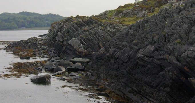 Shot looking down the rocky Shoreline of steeply inclined sedimentary rock like turbidite strata at Craignish Point, Sound of Jura.