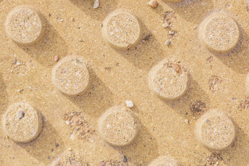 Tactile paving for pedestrian sidewalks and paths. Close-up of a textured tactile surface with a repeating dot pattern in warm sandy tones. Tactile indicator
