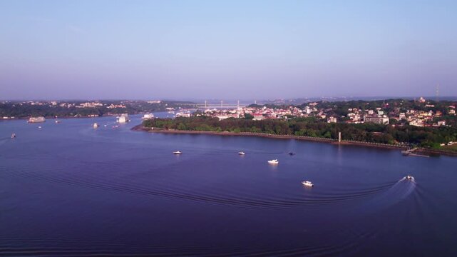 Mandovi River cruise ships with Panaji cityscape and greenery at goa. day time, trucking shot, drone shot, 4k.