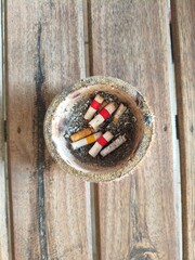 Bamboo ashtray with scattered cigarette ash on a wooden table