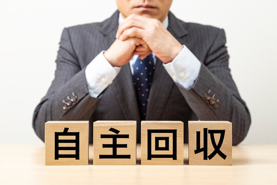 「自主回収」と書かれたブロックとビジネスマン