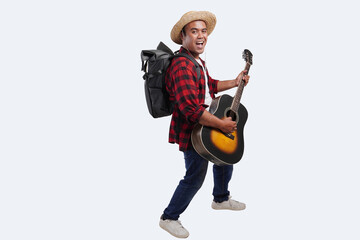 Naklejka premium Asian man tourist wearing a straw hat and a plaid shirt is enjoy playing a guitar, isolated white background