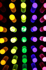 A Grid Of Illuminated Cylinders Glowing In Rainbow Colors Against A Black Background. Abstract Light Art Installation Or Physics Demonstration.