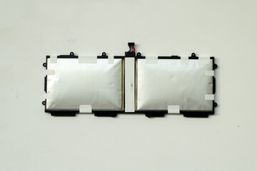 A pair of severely swollen silver lithium polymer battery cells for a laptop or tablet, removed from the device and shown isolated against a plain white background.