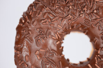 Extreme Close Up Of A Fresh Donut Covered In Rich Chocolate Frosting And Sprinkles. The Image Focuses On The Sweet Texture And Details Of The Confectionery.