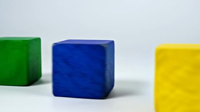 Three colorful, squarish blocks arranged diagonally across a white background. Each cube is a different color