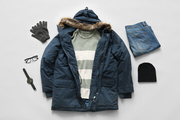 Stylish blue parka with winter accessories, jeans, sweater and wristwatch on grey background © Pixel-Shot