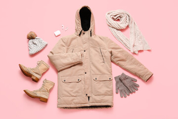 Stylish beige winter parka with boots, earphones and accessories on pink background © Pixel-Shot
