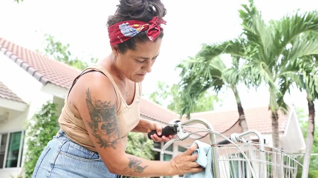 Tattooed woman carefully cleaning her bicycle handlebars outdoors