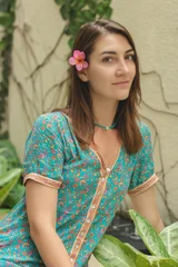 The portrait of beautiful brunette woman closeup on the green natural background with decorations. bali, indonesia © volhavasilevich