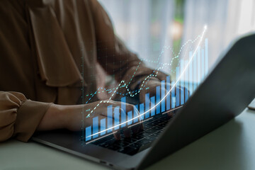 A business professional uses a laptop to analyze financial data, with a digital graph overlay illustrating growth trends and performance metrics in a modern office setting. Impute