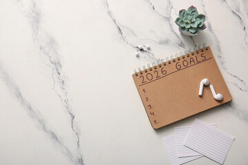 Notebook with text 2026 GOALS, earphones and stationery on grunge white background