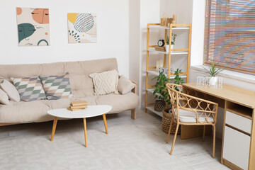 Interior of light living room with couch, plants and tables