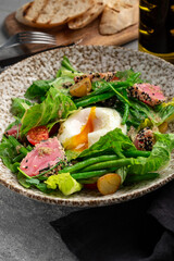 Fresh seared tuna salad with poached egg, green beans, potatoes, tomatoes and sesame seeds. Healthy gourmet meal, nutritious food photography on rustic plate, close up