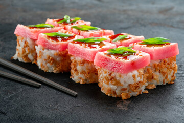 Elegant tuna sushi rolls topped with fresh raw tuna, teriyaki glaze, and green onions, served with chopsticks on dark slate. Luxury Japanese maki, gourmet tuna roll, premium seafood sushi, closeup