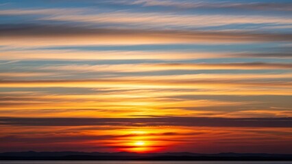 Fototapeta premium Stunning sunset over calm sea with vibrant clouds and distant hills in the background