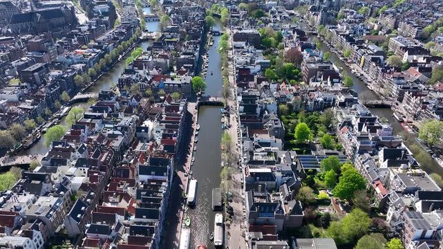 Beautiful aerial drone view from above, Amsterdam,  Netherlands. Narrow canals with bridges, street, boats, architectures lines of houses, famous sights and traffic around city downtown in Holland.4K