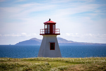 A White And Red Lighthouse Stands Tall On A Coastal Headland, on the Magdalen Islands, Quebec, Canada