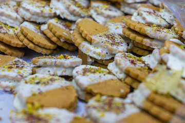 Stacked cookies filled with cream and topped with crushed pistachio. Traditional bakery sweets photographed at food market.