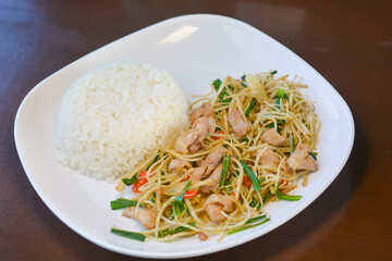 Stir-fried hooker’s chives or root su with chicken served with rice on a white dish. Yunnan food concept.