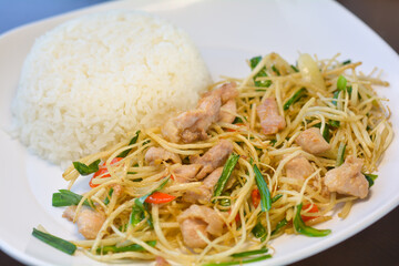 Stir-fried hooker&rsquo;s chives or root su with chicken served with rice on a white dish. Yunnan food concept. Close up