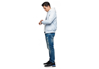 A young man in a light blue bomber jacket and distressed blue jeans, looking down at his wrist, isolated on transparent background