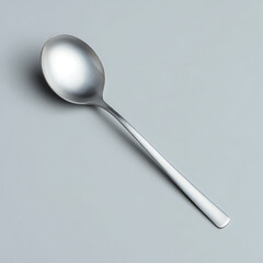 A single shiny silver metal soup spoon isolated on a neutral background