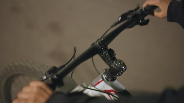 Closeup Bicycle Handlebar Turning Motion, Rider Steering Through Dimly Lit Path, Dynamic Angle Showing Front Wheel Alignment And Subtle Lean, Concentrated Movement And Evening Atmosphere