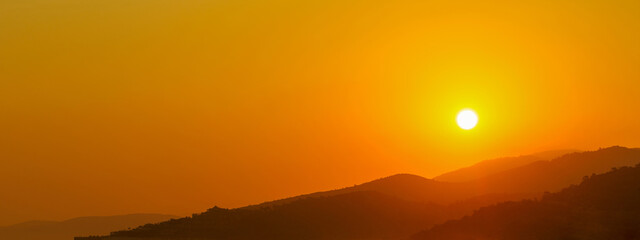 the sun rising behind a mountain