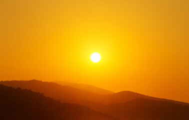 the sun rising behind a mountain