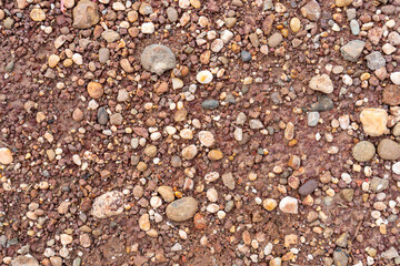 Textured gravel surface with various sizes of stones and pebbles, creating natural earthy...