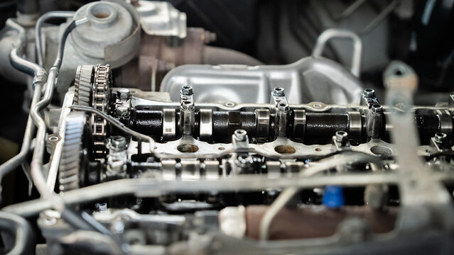 A close up of a car engine with a lot of oil on it. The engine is black and the oil is black as well