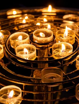 Lit Candles In A Circular Metal Holder In A Dark Church