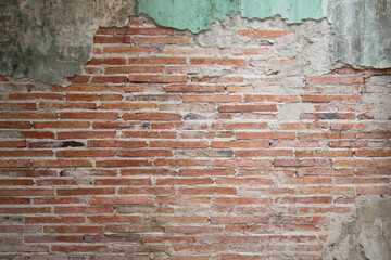 Grunge weathered brick wall texture with peeling, cracked green plaster and exposed red bricks. © Jitti