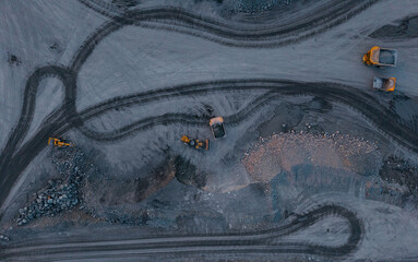 Aerial view of ore storage site with dump trucks and excavators on grey terrain © Parilov