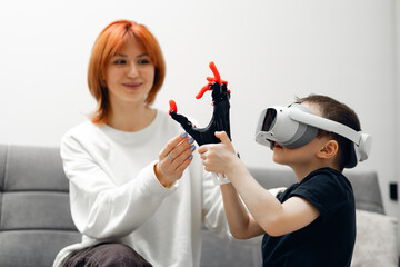Caucasian female adult with child boy using vr headset and toy robotic arm in modern setting