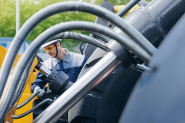 Machinery mechanic checks hydraulic hose system equipment on excavator. Concept industry truck maintenance